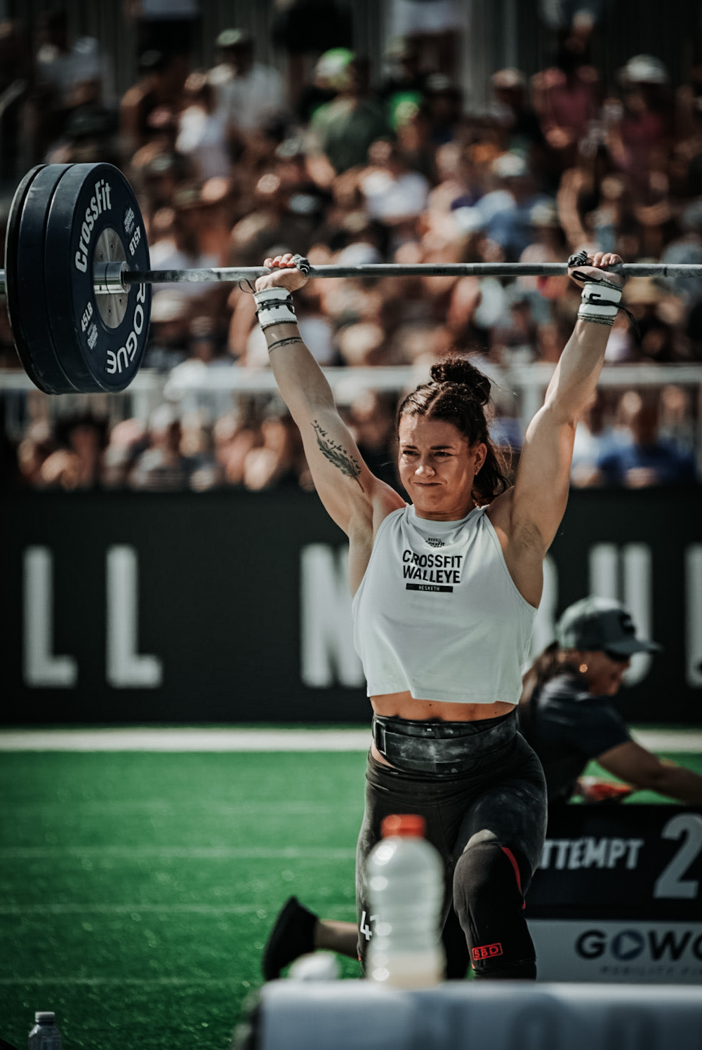 Athlete driving a loaded barbell overhead on a competition field